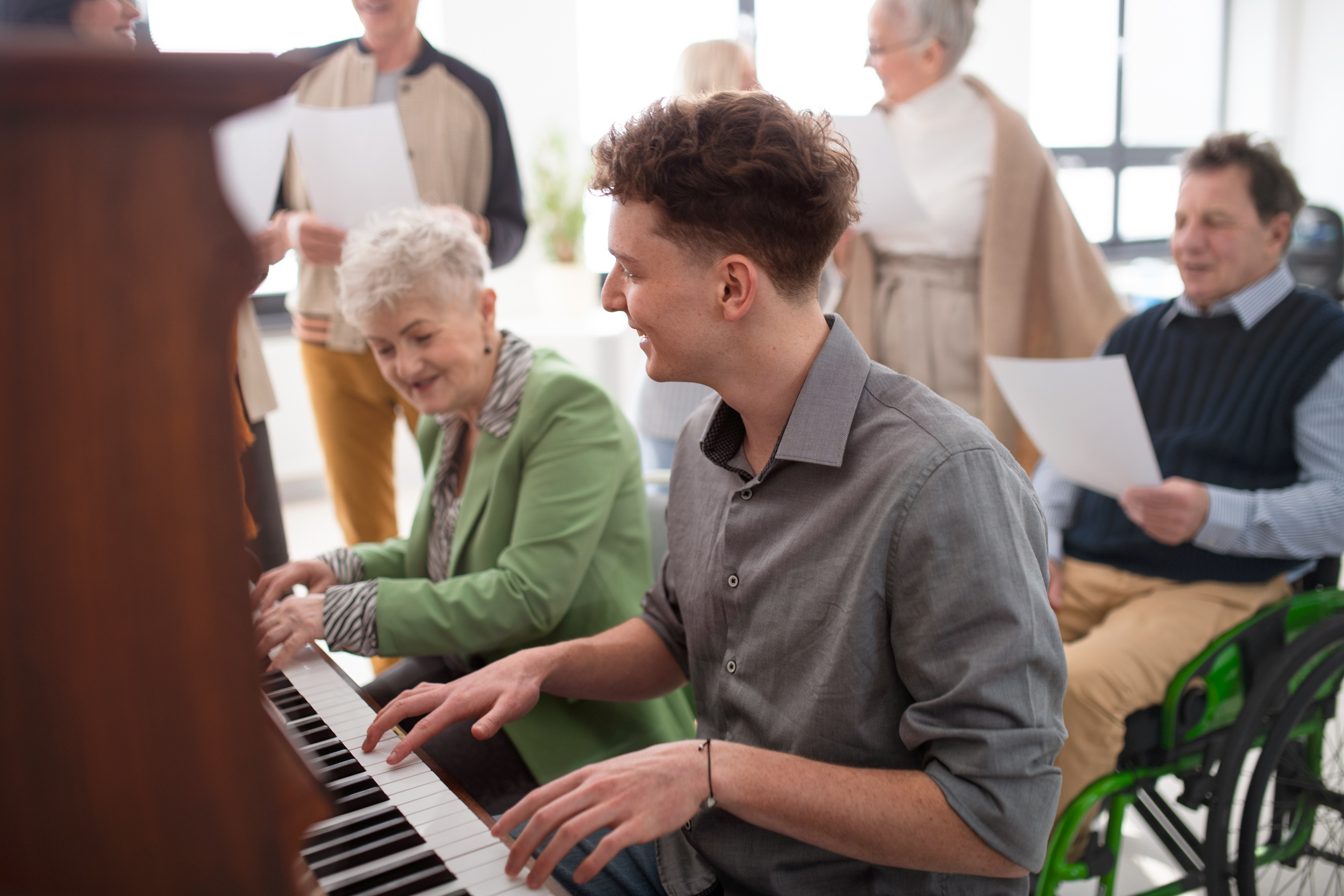 Photo d'un jeune homme et une femme agée en train de jouer du piano ensemble